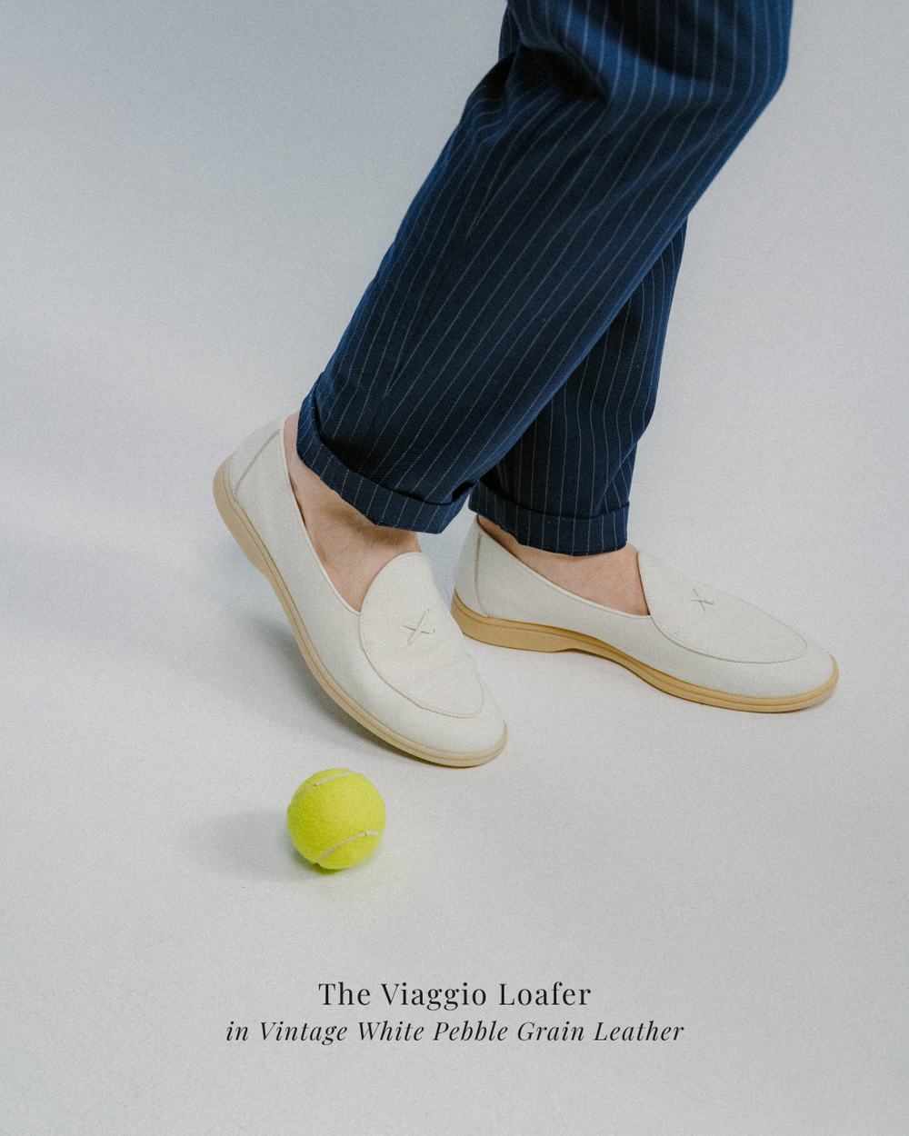 man wearing navy striped pants and white leather walking loafers with a gum sole