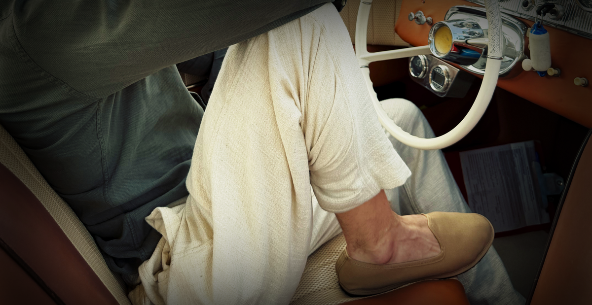 Man sitting in driver's seat of car wearing tan canvas friulane slippers