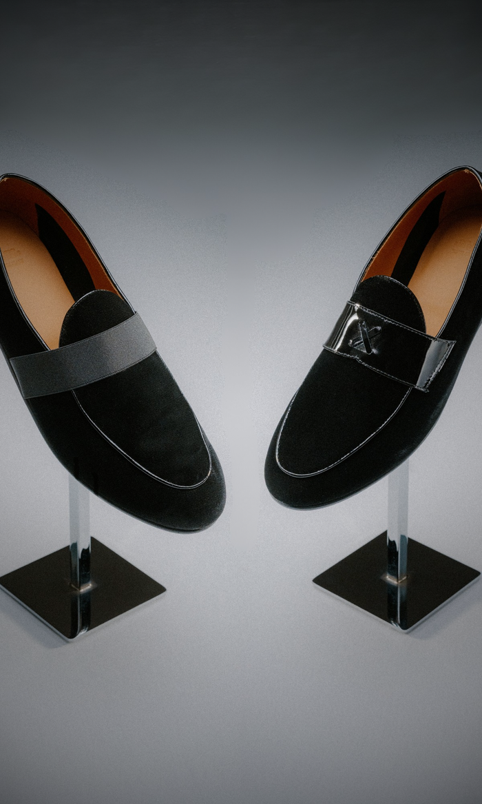 Black velvet loafers propped up on a shoe stand