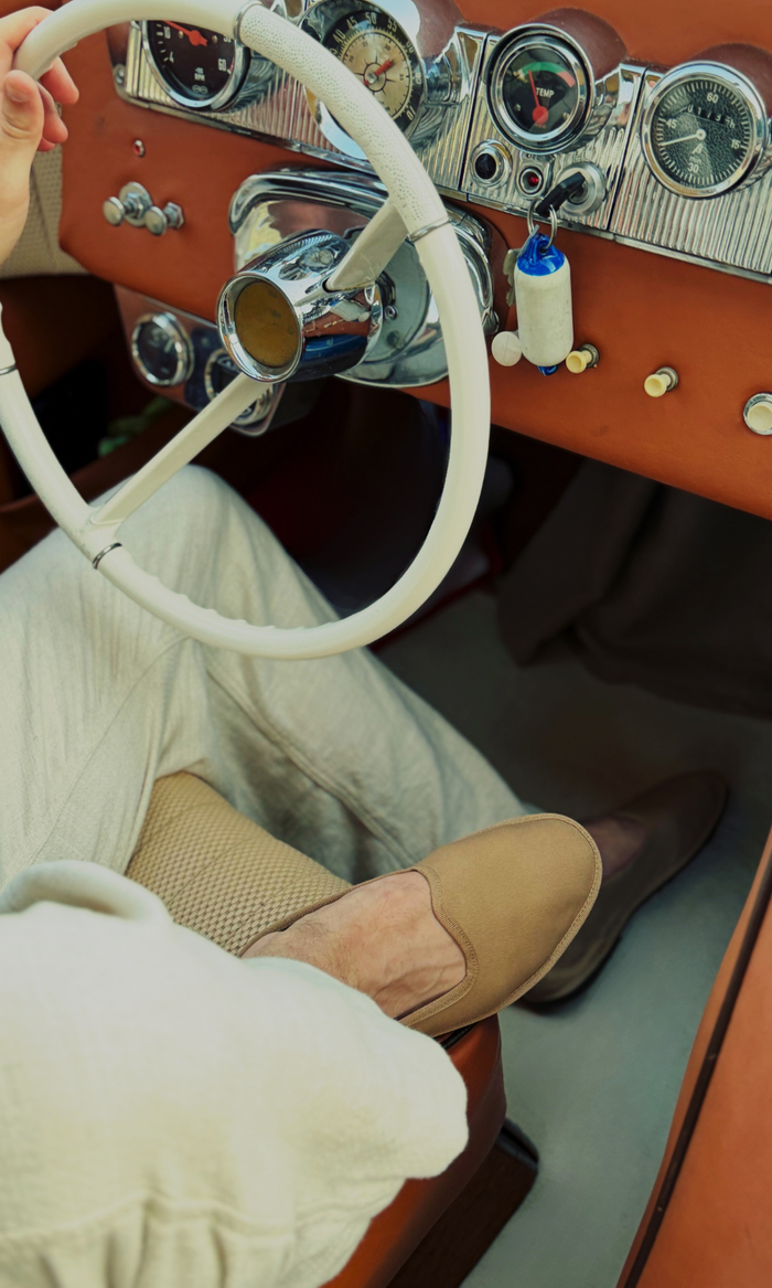 Man sitting in driver's seat of car wearing tan canvas friulane slippers